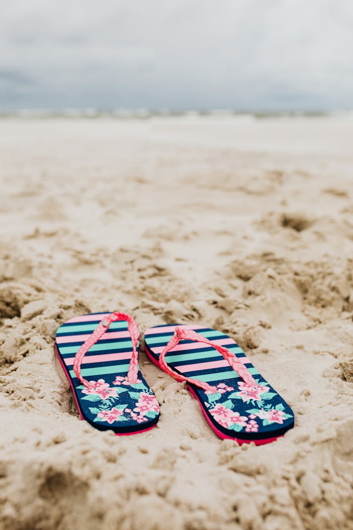 services-02 Vibrant flip flops resting on sandy beach, evoking a tropical summer vibe.
